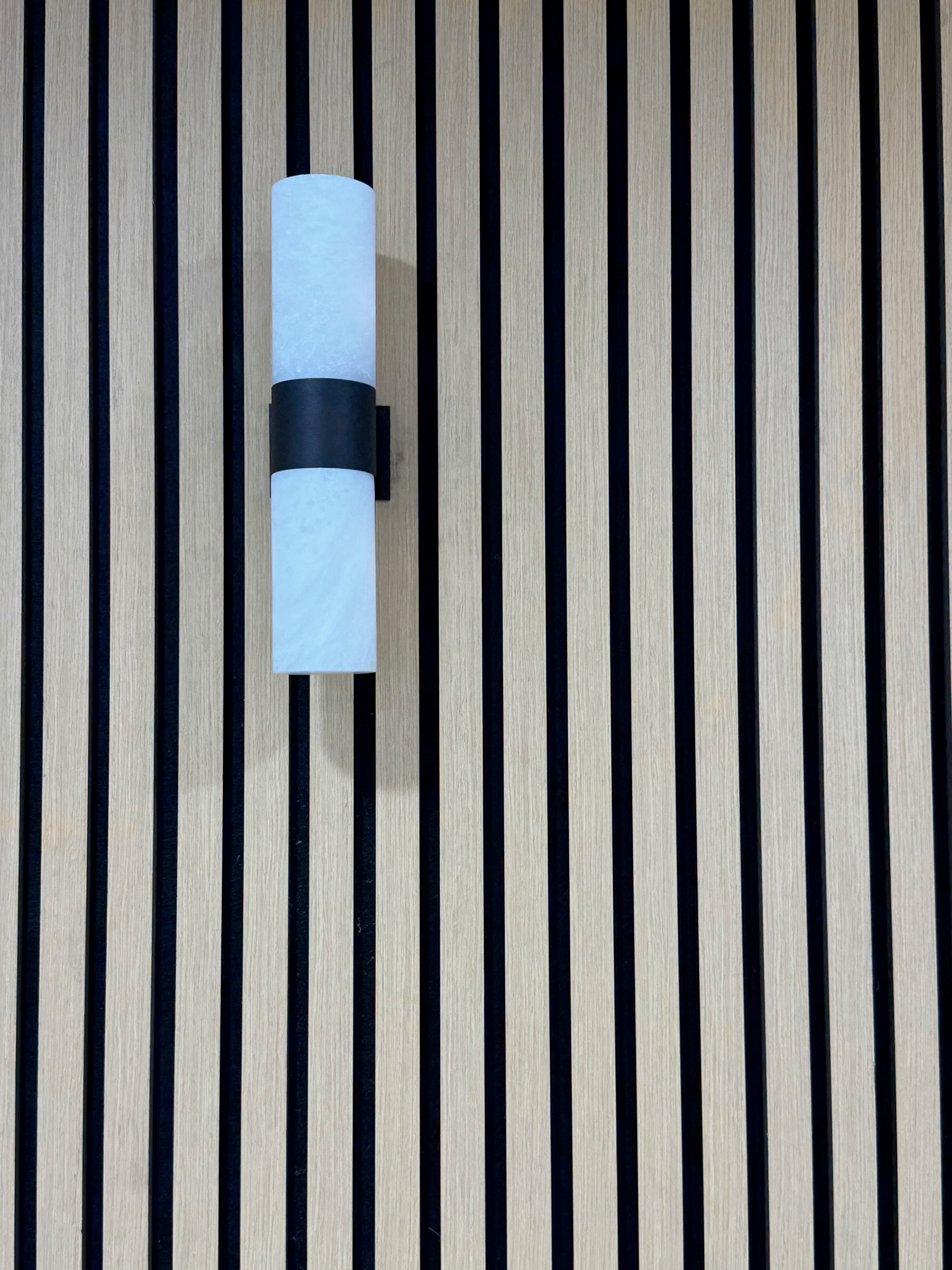 Minimal wall-bracket light on acoustic natural oak slat panel at Elixir Aesthetic, East Perth